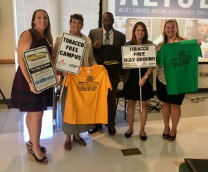 Members of Tobacco Free Living team holding signs and shirts advertising Smoke Free Holy Grounds